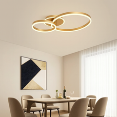 Lustra LED cu doua inele aurii suprapuse si telecomanda, montata in zona de dining, oferind luminare clara si stil modern elegant.